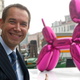 The artist behind “Balloon Dog (Magenta), with the work…behind him.